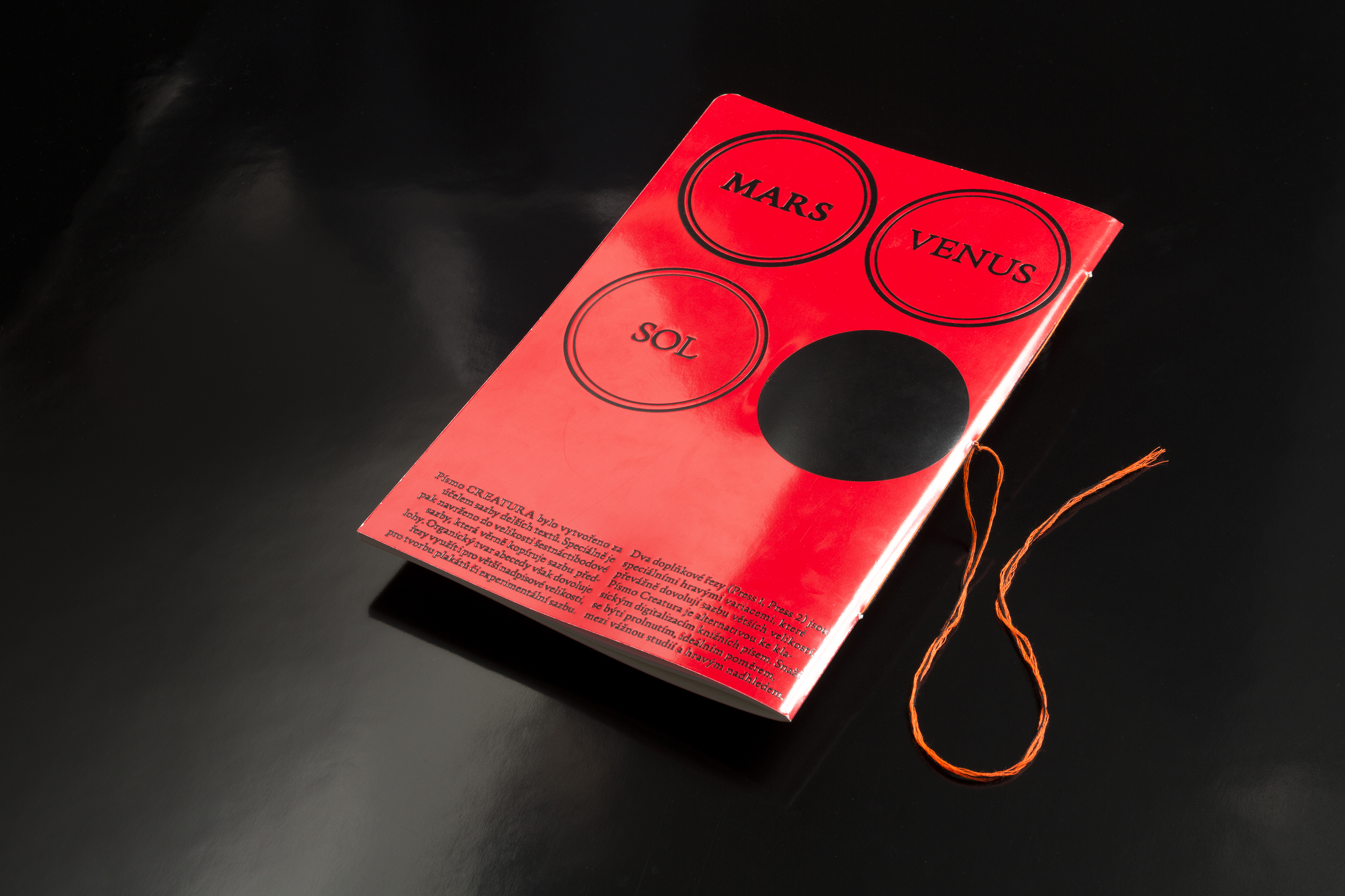 The back cover of the Creatura font specimen is in red with circular designs labeled 'Mars,' 'Venus,' and 'Sol.' The design alludes to cosmic and mythological themes, aligning with the catalog's conceptual and artistic explorations.