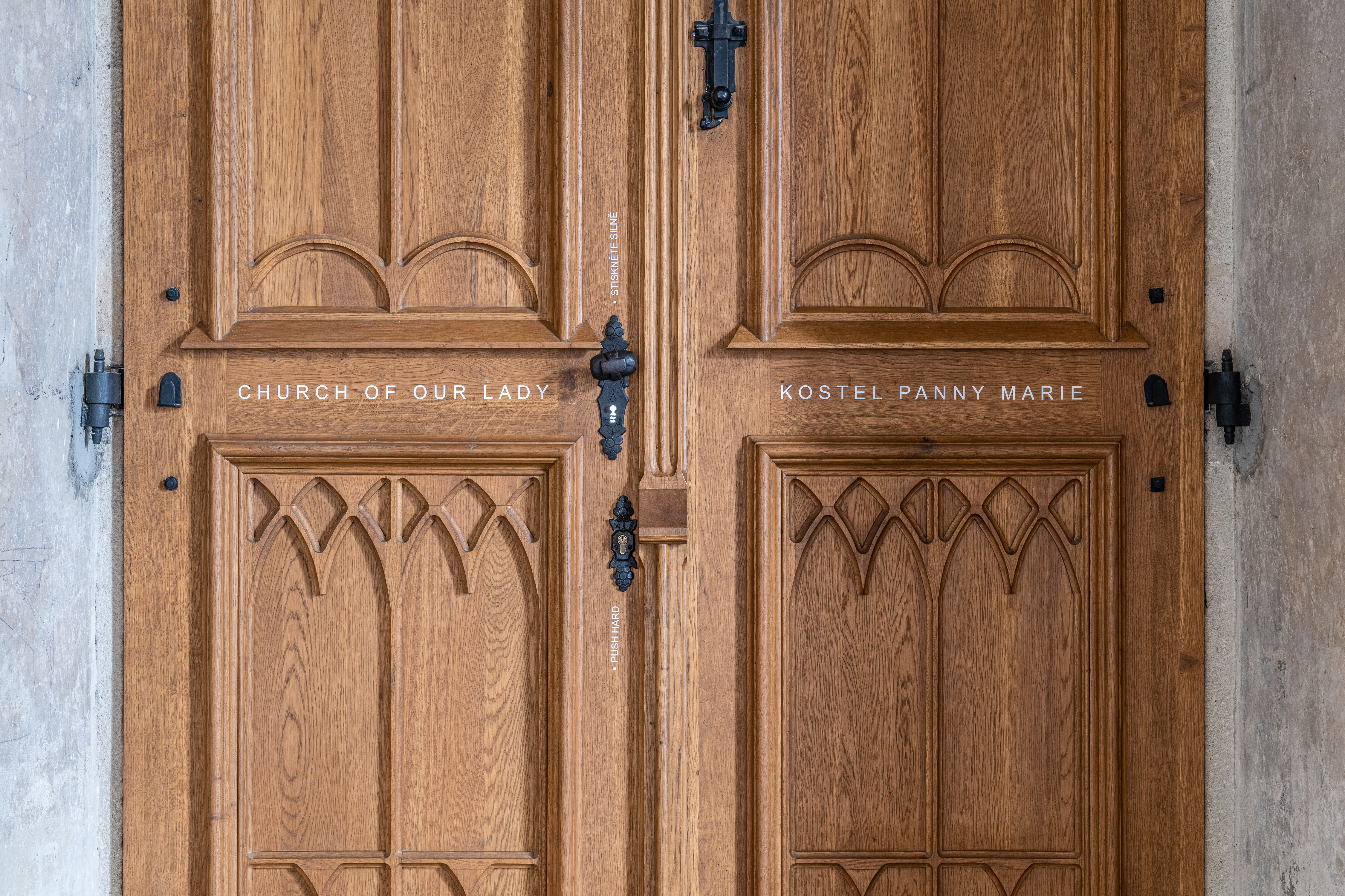 Entrance to the Church of Our Lady at Emmaus Abbey, featuring wooden double doors engraved with typographic labels, aligned with the abbey's modest identity and navigation system.