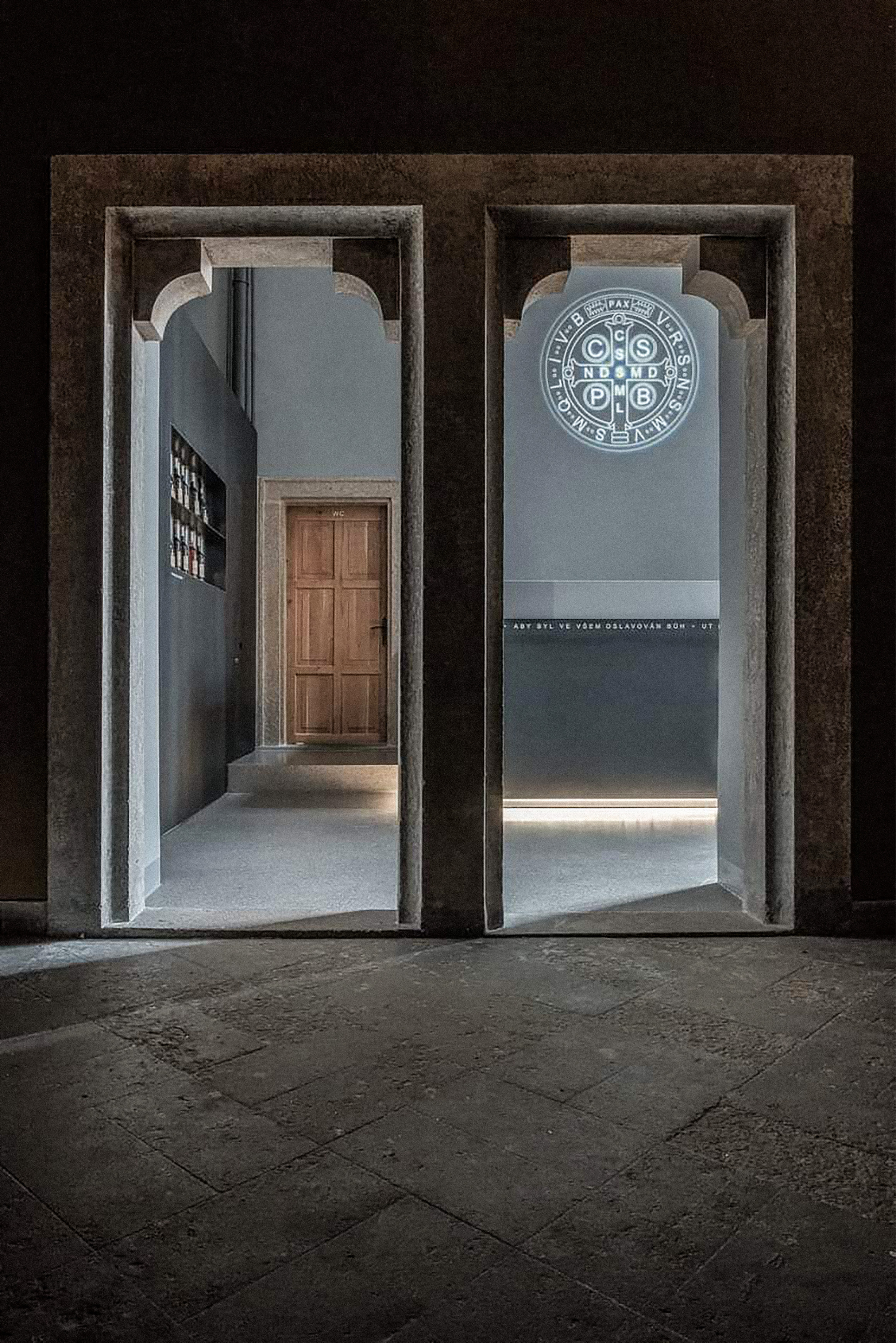 An interior stone archway with Benedictine seals at Emmaus Abbey showcases minimalist and typographic-focused navigation inspired by modesty and the abbey's identity.