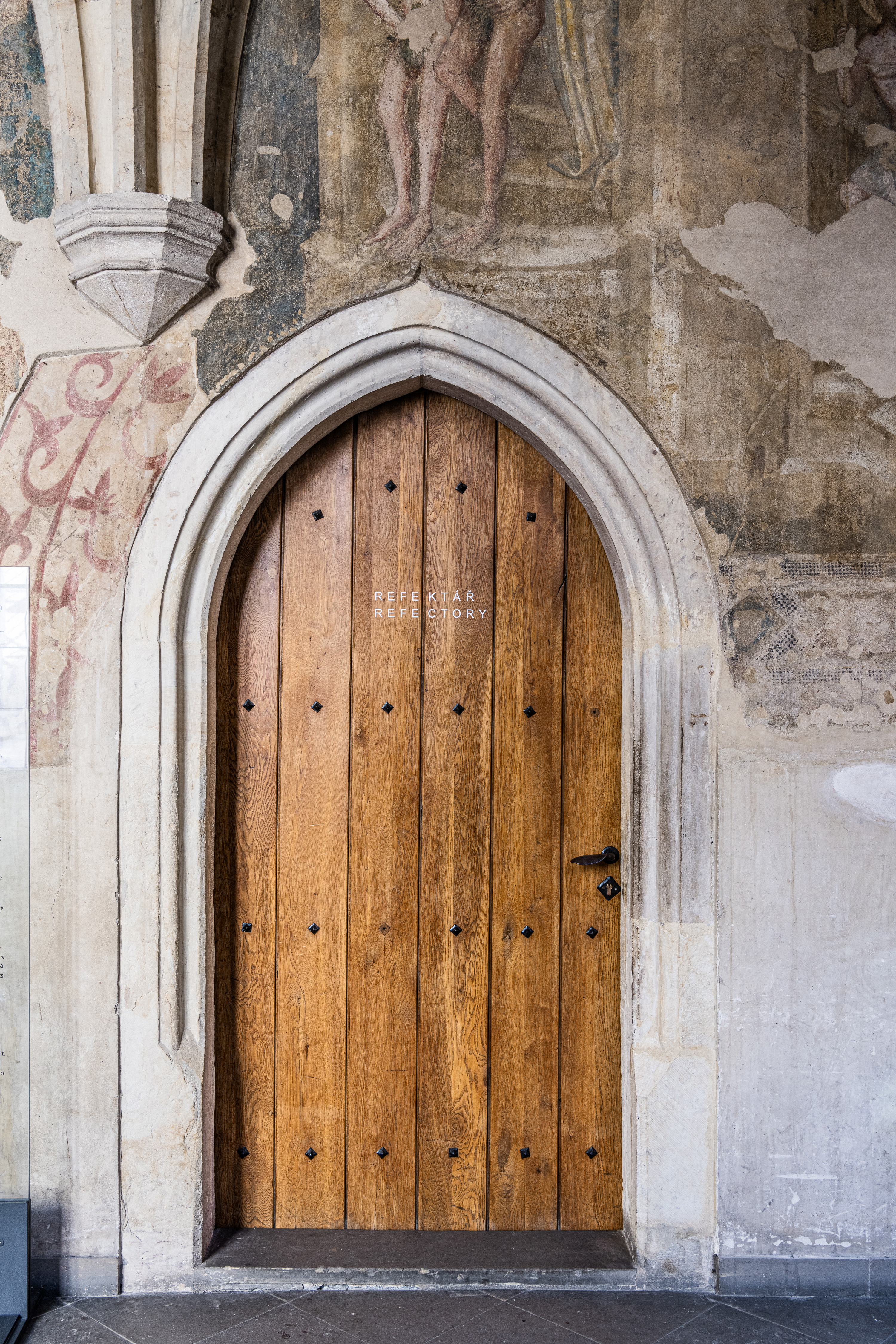 The wooden door labeled 'Refectory' at Emmaus Abbey, framed by ancient stone combines historical architecture with the abbey's modern, modest identity and typographic navigation style.